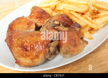 Un plat de service empilé avec citron et de cuisses de poulet rôti frites, ou des jetons, avec une cuillère à dessert Banque D'Images