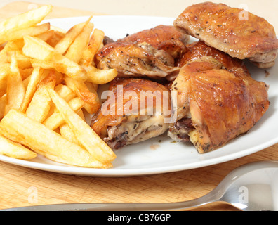 Un plat de service empilé avec citron et de cuisses de poulet rôti frites, ou des jetons, avec une cuillère à dessert Banque D'Images