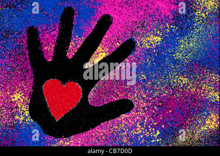 Childs hand imprime avec coeur rouge formes confectionnées avec de la poudre de couleur sur fond noir Banque D'Images