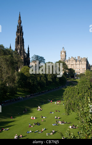 Les touristes vous détendre dans les jardins de Princes Street à l'Est par le Scott Monument à Édimbourg. C'est une belle journée chaude car les gens se détendre dehors. Banque D'Images