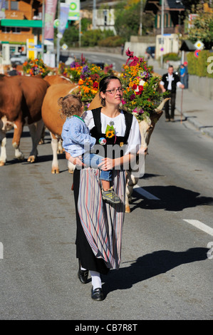 La Desalpe. Femme suisse en costume traditionnel portant sur les vaches des Alpes et à travers la ville Banque D'Images