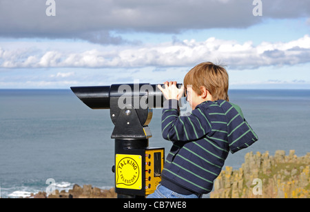 Un jeune garçon à l'aide d'un télescope à Lands End en Cornouailles, Royaume-Uni Banque D'Images