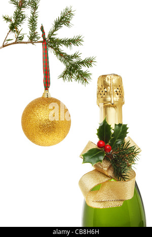 Bouteille de champagne, champagne de Noël décoré de ruban et holly avec une boule d'or suspendu à une branche d'arbre de Noël Banque D'Images