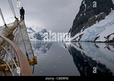 Bateau à voile avec l'homme sur le beaupré à la recherche dans le Canal Lemaire / Écart Kodak, l'Antarctique Banque D'Images