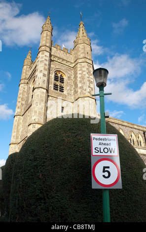 Une limite de vitesse de circulation cinq mph signer contre une haie d'ifs taillés, St Mary's Parish Church tower Beaconsfield dans l'arrière-plan Banque D'Images
