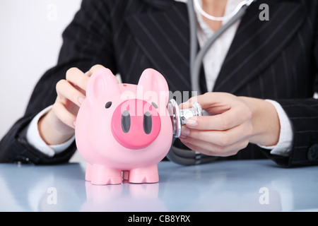 Gros plan sur l'examen de pink piggy bank par caucasian businesswoman. Banque D'Images