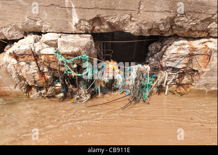 Masse de cordes nylon vieilli et filets de pêche accroché à une défense en béton de l'aine Banque D'Images