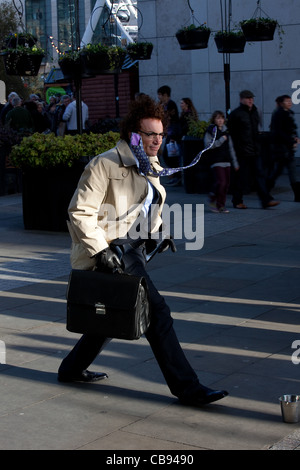 "L'homme pressé" - Artiste stationnaire immobile sur les rues de la ville, avec porte-documents et des taux élevés d'égalité se raidit, Manchester UK Banque D'Images