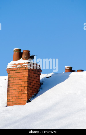 Une cheminée sur le toit couvert de neige d'une maison au Royaume-Uni Banque D'Images
