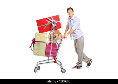 Jeune homme en poussant un chariot plein de cadeaux Banque D'Images