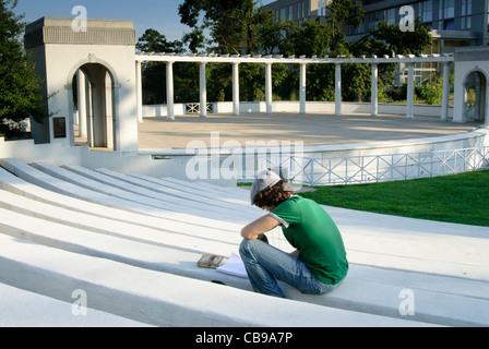 College student reading et relaxant au Théâtre grec sur le campus de l'Université de l'Arkansas à Fayetteville. Banque D'Images