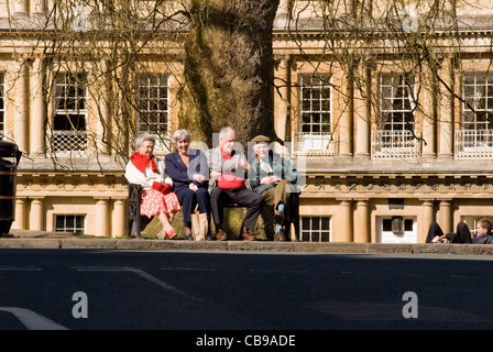 Deux dames et deux messieurs assis sur un banc de parc en centre-ville de Bath, Angleterre, Royaume-Uni Banque D'Images