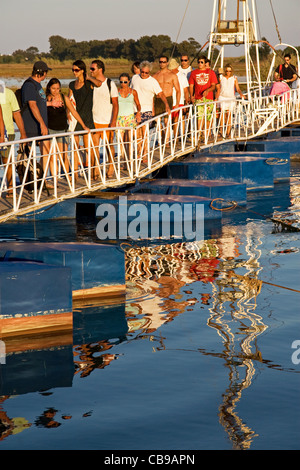 Les vacanciers de retour en soirée sur le pont flottant de la plage de Barril sur Ilha de Tavira. Pedras d'el Rei. Algarve, Portugal. Banque D'Images