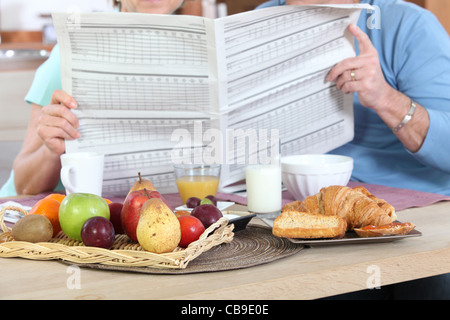 Couple reading newspaper pendant le petit déjeuner Banque D'Images