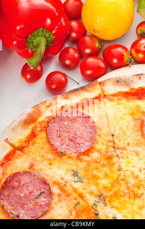 D'origine italienne pizza au pepperoni à croûte mince avec des légumes frais en arrière-plan Banque D'Images