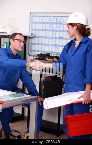 Les employés manuels shaking hands in office Banque D'Images