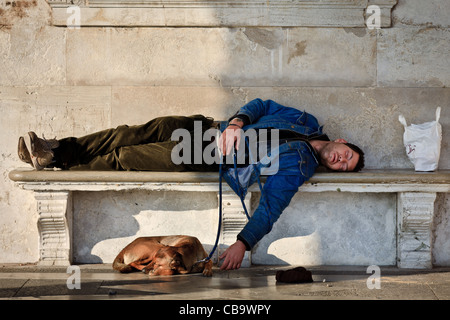 Sans-abri avec son chien endormi sur un banc à Venise, Italie Banque D'Images