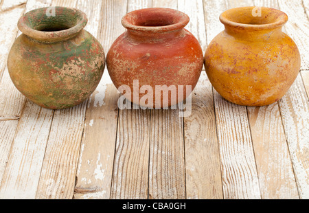 Trois petits pots en argile (de masse produits semoir) à surface rugueuse, grunge, finition blanc sur fond de bois rustique Banque D'Images