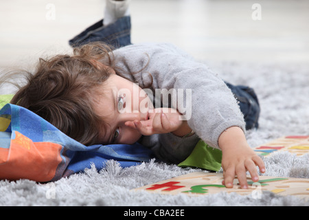 Enfant gisant sur le sol à jouer avec un puzzle Banque D'Images