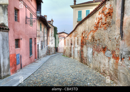 Rue étroite pavée entre les maisons anciennes et anciens remparts en Saluzzo, Italie du nord. Banque D'Images
