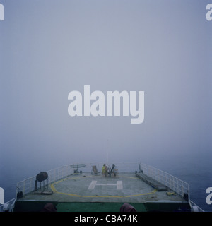 L'équipage assis sur héliport pont d'un navire, dans le brouillard, en mer. Banque D'Images