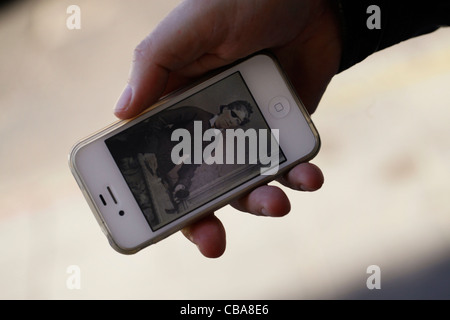 Une personne titulaire d'un Apple Iphone téléphone cellulaire de l'affichage d'une photographie vintage Banque D'Images