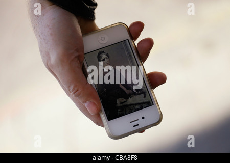 Une personne titulaire d'un Apple Iphone téléphone cellulaire de l'affichage d'une photographie vintage Banque D'Images