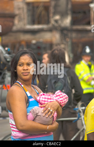 Une jeune mère - bébé dans les bras- enquêtes incrédule la destruction Tottenham High Rd subi du fait de l'émeute. 06.08.2011 Banque D'Images