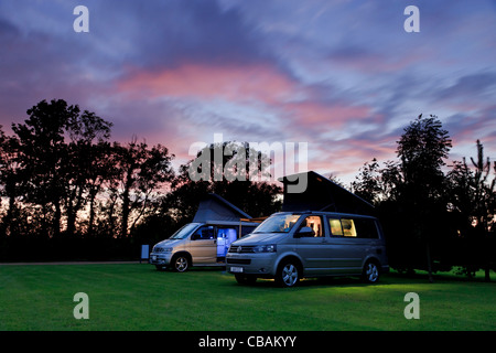 Un VW Califonia et une Mazda Bongo camper van côte à côte sur un camping au coucher du soleil Banque D'Images