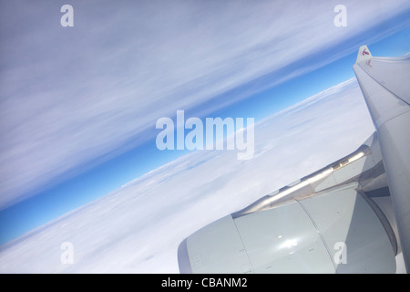 Vue à travers la fenêtre du passager jet avion de Qatar, aile Ciel et nuages Banque D'Images