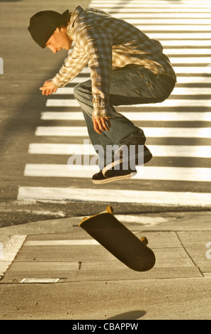 Un homme fait un ollie skateboarder jump trick sur un trottoir. Banque D'Images