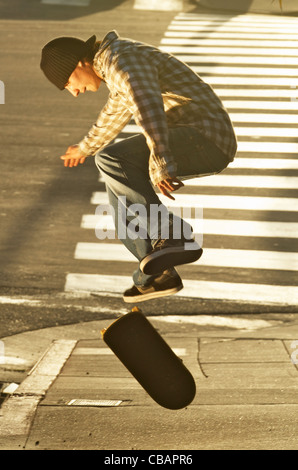 Un homme fait un ollie skateboarder jump trick sur un trottoir. Banque D'Images