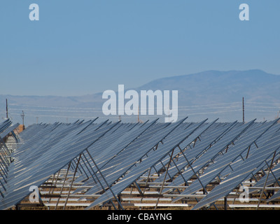 Une série de grands panneaux solaires forme une ligne symétrique à une centrale électrique dans la vallée de San Luis Colorado central. Ces panneaux utilisent un système de suivi pour suivre le soleil, la collecte de l'énergie et l'utilisation de cellules photovoltaïques pour transformer la lumière du soleil en électricité. Banque D'Images