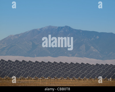 Une série de grands panneaux solaires forme une ligne symétrique à une centrale électrique dans la vallée de San Luis Colorado central. Ces panneaux utilisent un système de suivi pour suivre le soleil, la collecte de l'énergie et l'utilisation de cellules photovoltaïques pour transformer la lumière du soleil en électricité. Banque D'Images