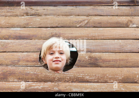 Boy peeking through hole dans playhouse Banque D'Images