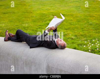 Businessman reading newspaper in park Banque D'Images