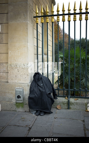 Les sans-abri en forme de bourse du jardin des plantes., dormir assis au pied de pikes. Banque D'Images