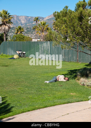 Une trentaine de sans-abri quelque chose qui peut accueillir jusqu'à midi sur l'herbe verte d'un parc de la ville avec son vélo. Banque D'Images