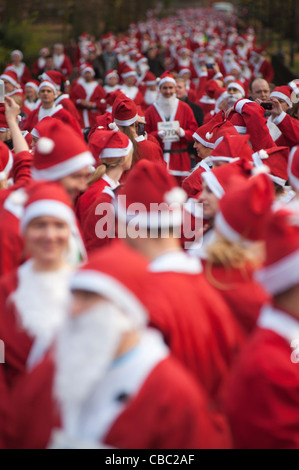 Des gens habillés en Père Noël se préparent à prendre part à l'organisme de bienfaisance annuel 10k Santa Run dans Battersea Park, Londres. Banque D'Images