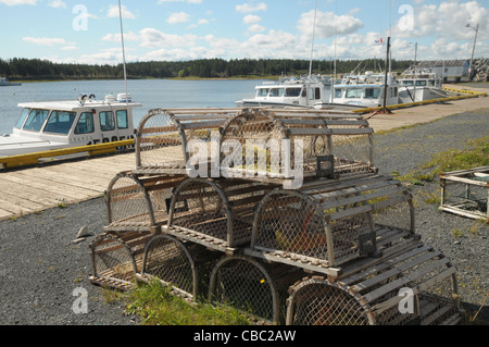 Les casiers à homards grace le premier plan comme les bateaux de pêche sont liés aux quais dans le port de North Lake Harbour, Î. Banque D'Images