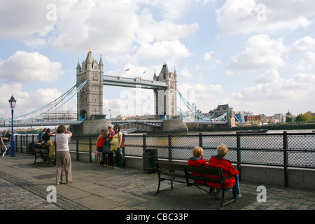 Les vacanciers ayant leur photo prise par une dame sur la rive de la Tamise avec le Tower Bridge en arrière-plan Banque D'Images