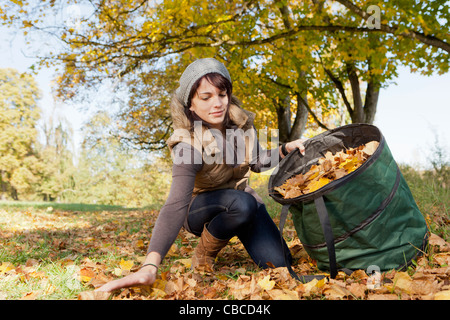 Collecte de feuilles d'automne femme in park Banque D'Images