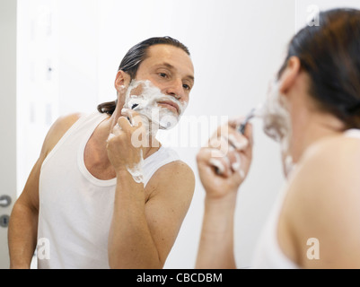 Rasage homme son visage dans la salle de bains Banque D'Images
