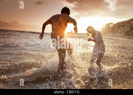 Couple playing in waves at beach Banque D'Images