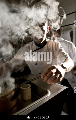 Chefs travaillant en cuisine commerciale, obscurcissant la vapeur visage Banque D'Images