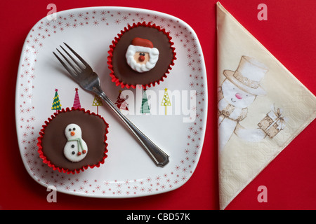 Le Snowman cupcake cupcakes et Santa des gâteaux sur la plaque de l'arbre de noël et bonhomme de neige serviette sur fond rouge Banque D'Images
