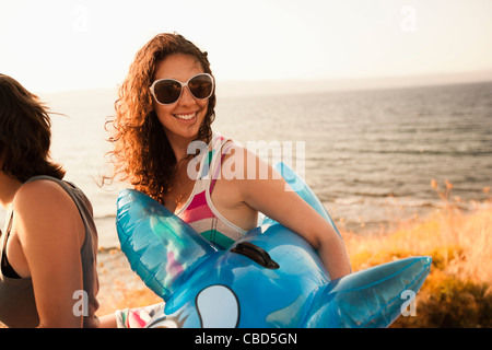 Femme transportant inflatable toy on beach Banque D'Images