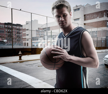 Man carrying basket-ball on city street Banque D'Images