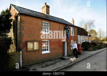 Blacksmith Keith Mahoney fixe le village d'Avebury shop signer avant son ouverture le dimanche matin Wiltshire UK (15 mars 2009) Banque D'Images