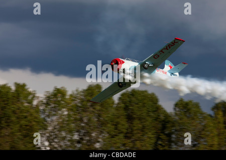 Yakovlev Yak-52 'Betsy' G-TYAK en vol la fumée à Breighton Airfield Banque D'Images